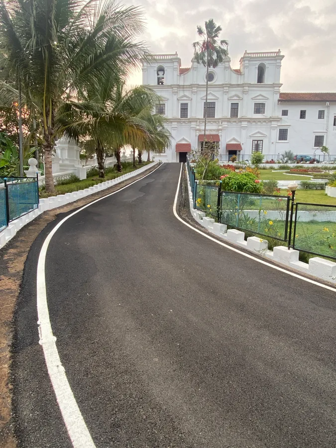 Newly resurfaced asphalt road leading to historic church in Curtorim